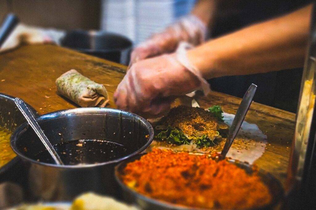 Close-up of fresh popiah being prepared with lettuce and crushed peanuts.