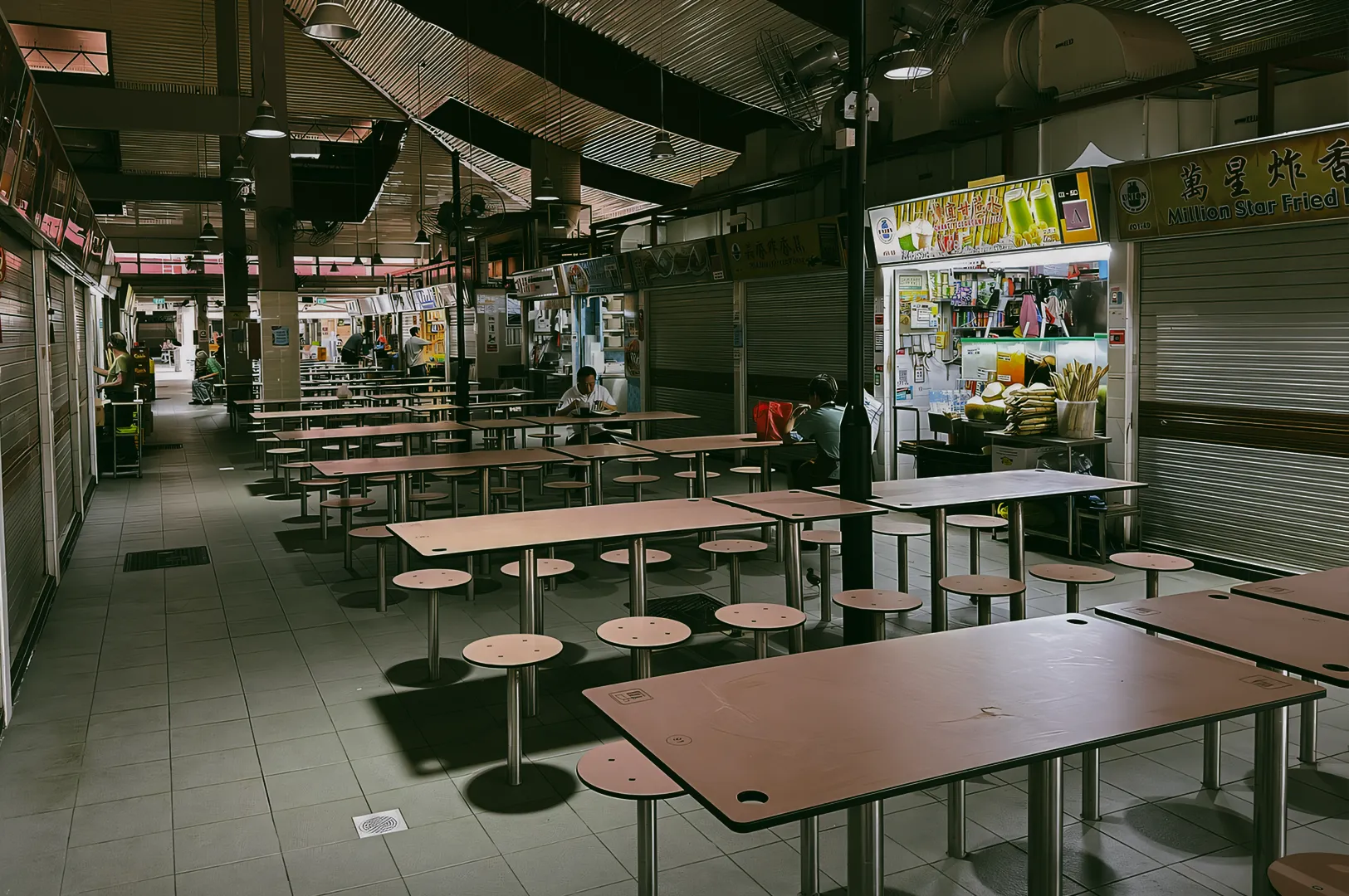 Interior of Changi Village Hawker Centre during a quiet period, showing empty tables, open food stalls, and shuttered units.