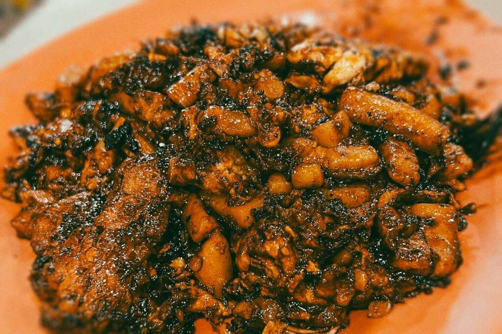 A plate of dark, caramelized fried carrot cake with chunky radish cake pieces coated in a rich savory sauce.