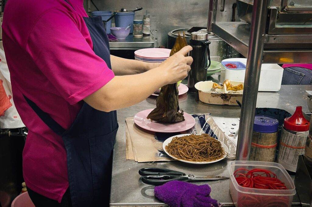 Busy kitchen scene with noodles and ingredients.