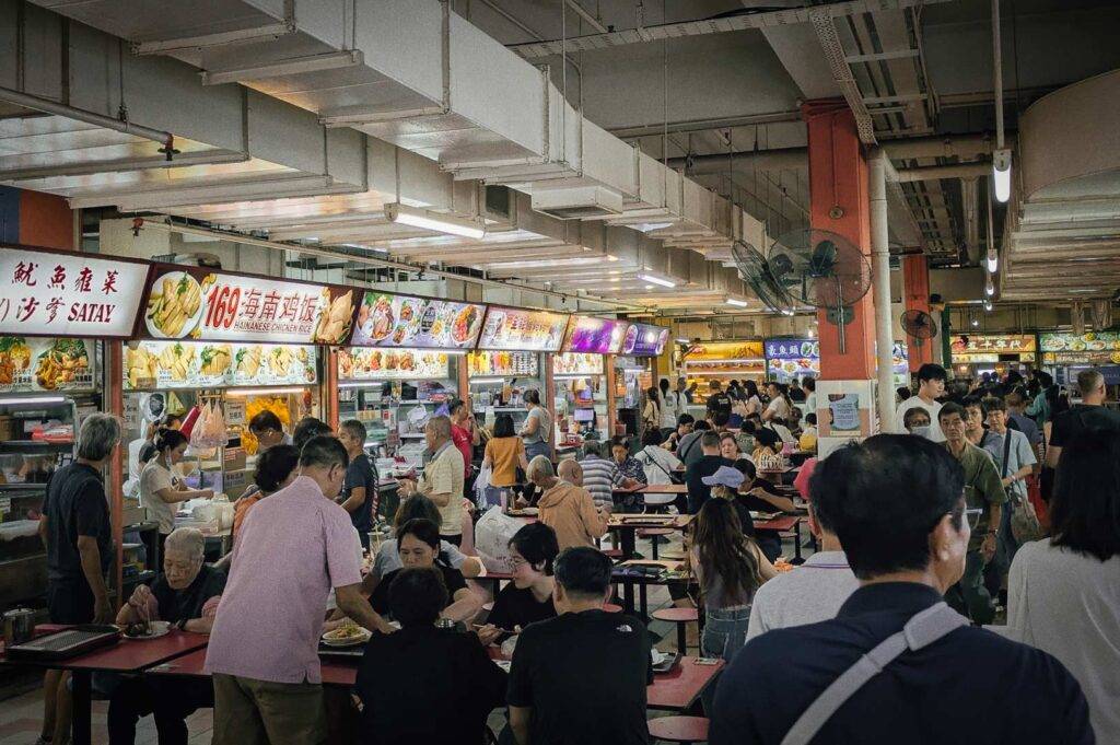 Bustling hawker center dining scene with red tables.