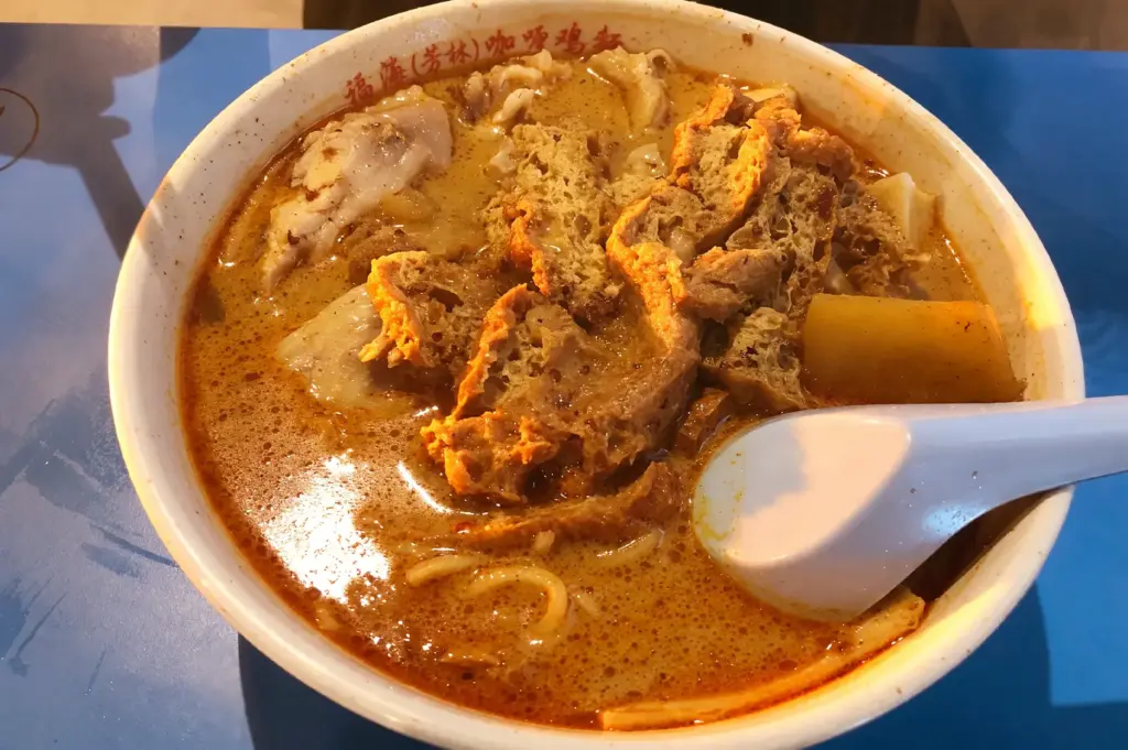 Laksa on a table—spoon resting against the bowl