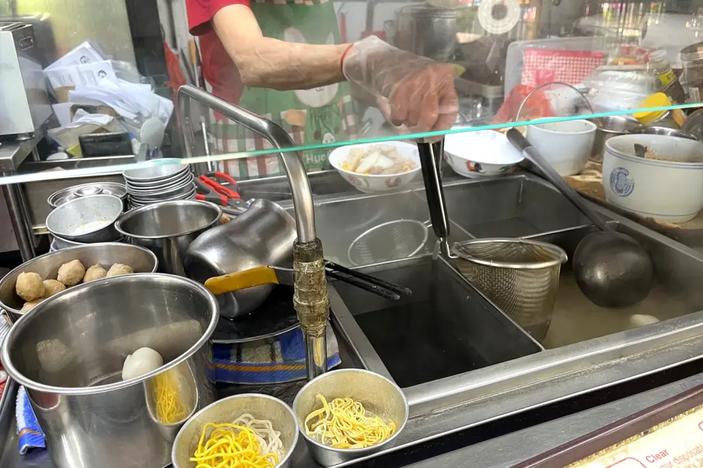 A stall worker preparing bowls while diners move through the background