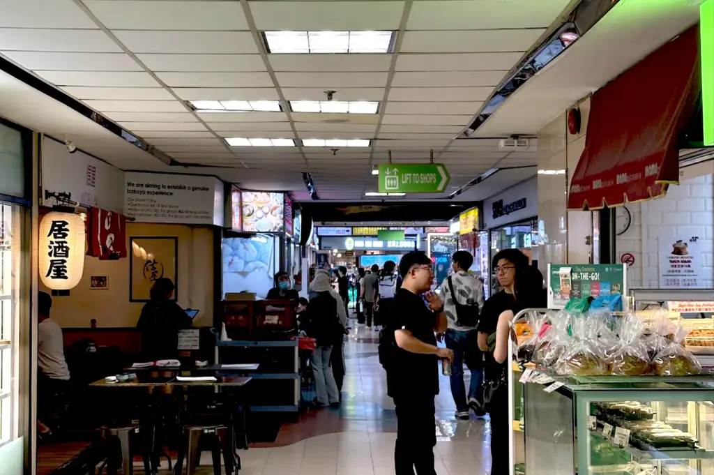 The bustling interior corridors of Fortune Centre, filled with diners and shoppers, reflecting the building's vibrant daily rhythm and familiar narrow walkways.