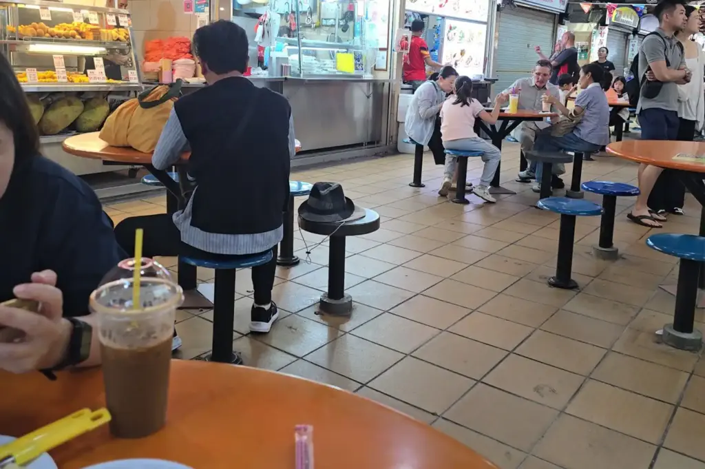 A hawker center dining area after hours, capturing the quiet post-closing cycle of cleaning, arranging, and preparation for the next day.